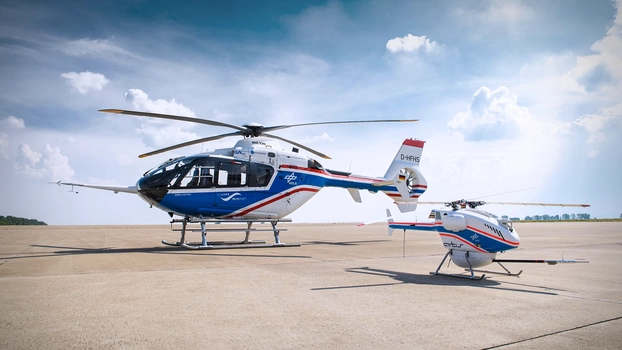 Ein Hubschrauber und eine Drohne des DLR auf einem Flugplatz am Boden.